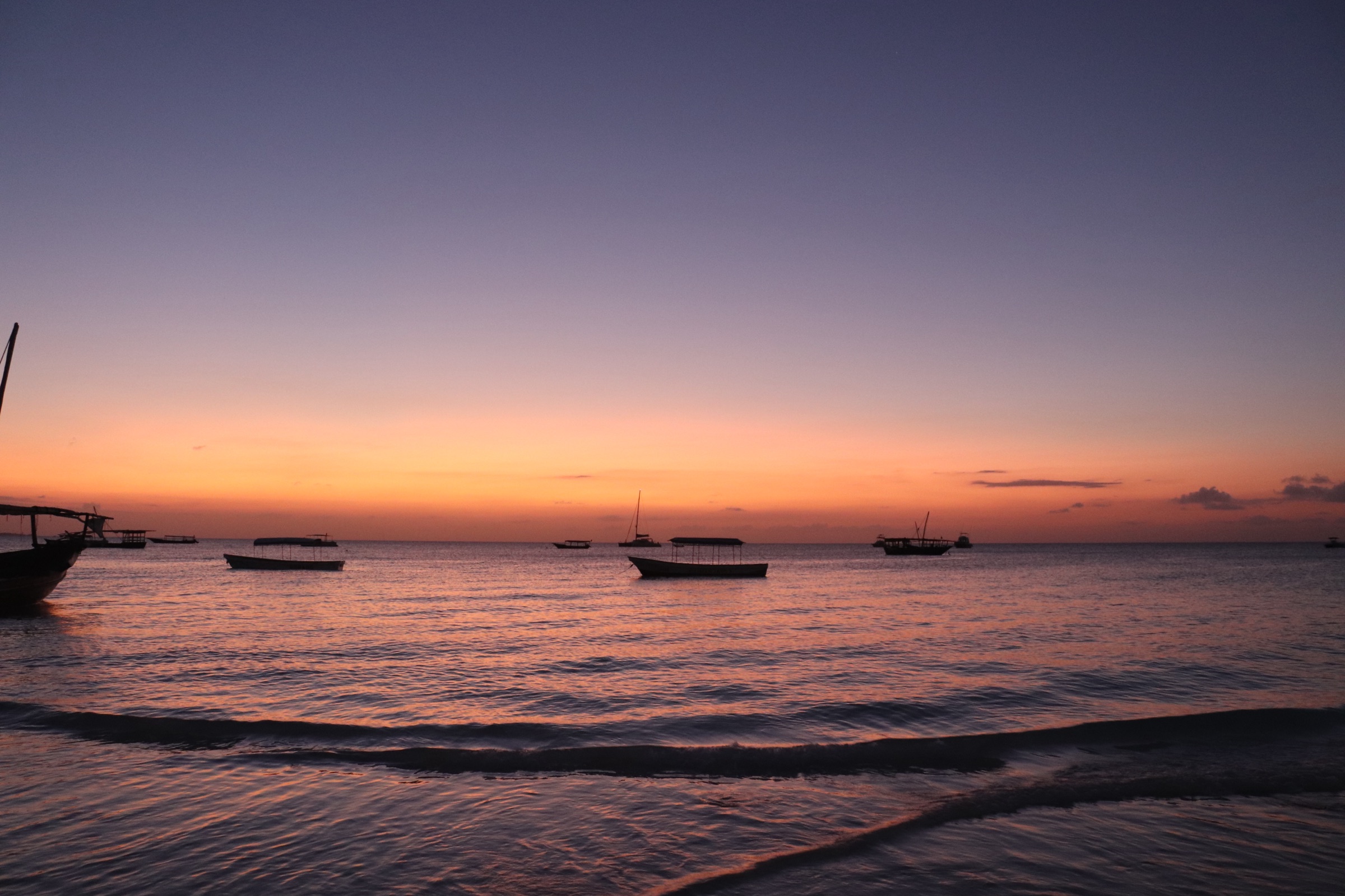 Traditional dhows silhouetted against a Zanzibar sunset
